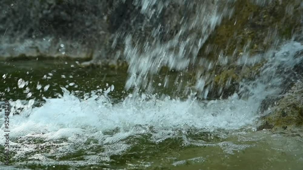Clear water from a waterfall is falling into a natural pool with green water in the mountains (slow motion, close up) Clear water from a waterfall is falling into a natural pool with green water in the mountains (slow motion, close up)