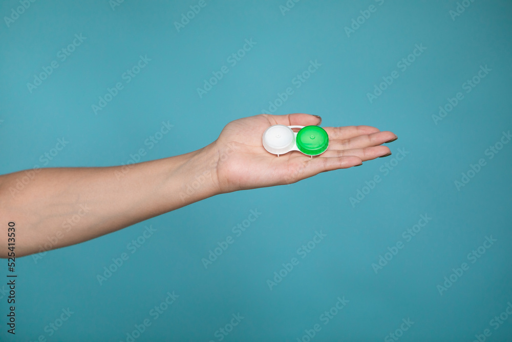 Lady holding case for contact lenses. Closeup image of container for contact lenseson blue background in studio. Lady holding case for contact lenses. Closeup image of container for contact lenseson blue background in studio.