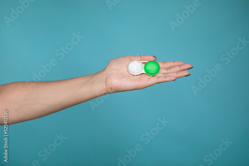 Lady holding case for contact lenses. Closeup image of container for contact lenseson blue background in studio.