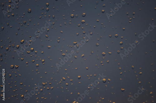 rain drops on the window on the sunset. blue background with orange drops. 