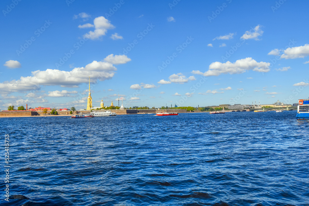 Boats tour and cruise on the Neva River with the Peter and Paul Fortress in view across the embankment in the historic center of Saint Petersburg, Russia.