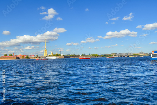 Boats tour and cruise on the Neva River with the Peter and Paul Fortress in view across the embankment in the historic center of Saint Petersburg, Russia.