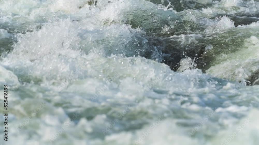 Sun shines on rapid river water, closeup abstract detail, slow motion video