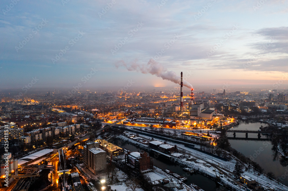 Aerial view of the evening Polish city of Wroclaw, the panorama of the old European city from a height. In the distance, above the city, large smoking chimneys of a thermal power plant can be seen.