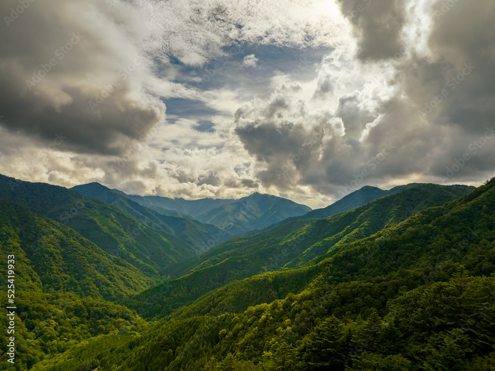 Naklejka premium Rain clouds close in on forested valley in high mountains