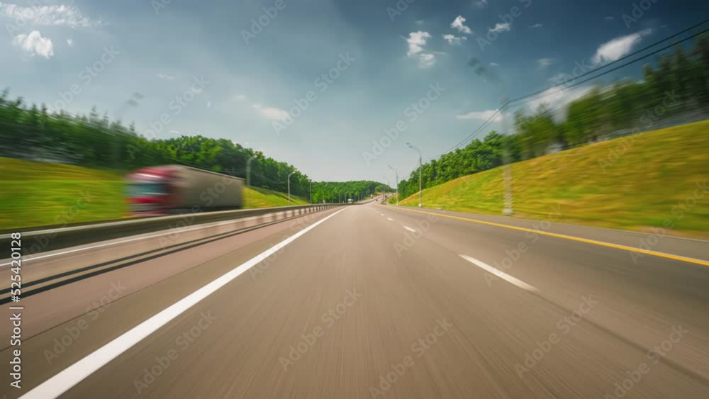 Motion timelapse of a speedy road drive along the highway on a sunny summer day. Front view from the car window to the road and beautiful surrounding countryside.