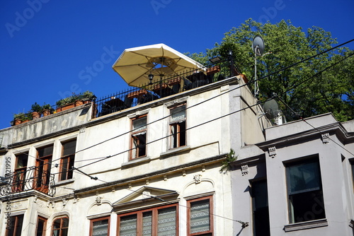 Dachterrasse mit Sonnenschirm vor blauem Himmel auf einem Altbau in Beige und Naturfarben in der Istiklal Caddesi in Taksim und Beyoglu in Istanbul am Bosporus in der Türkei photo