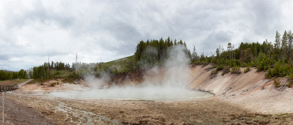 Hot spring Geyser with colorful water in American Landscape. Cloudy Sky. Yellowstone National Park, Wyoming, United States. Nature Background Panorama Hot spring Geyser with colorful water in American Landscape. Cloudy Sky. Yellowstone National Park, Wyoming, United States. Nature Background Panorama