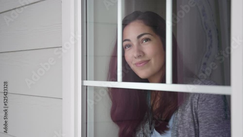 Hopeful, happy, excited woman smiles knowingly as she looks outside window photo
