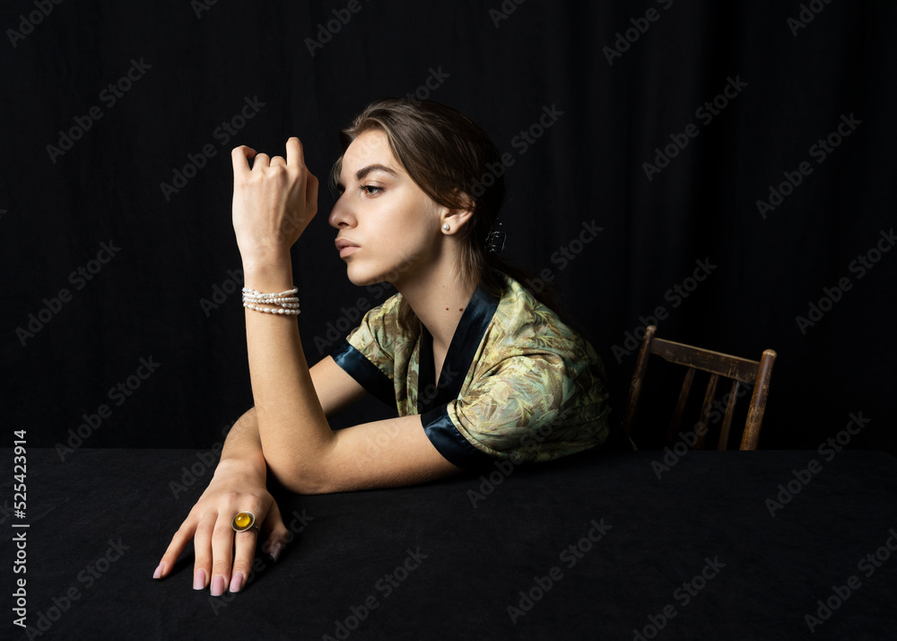 portrait of a beautiful woman with pearl jewelry and a bright ring on a black background sitting at a table portrait of a beautiful woman with pearl jewelry and a bright ring on a black background sitting at a table