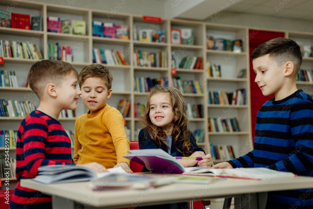 school children in the library reading books, doing homework, prepare a school project for lessons