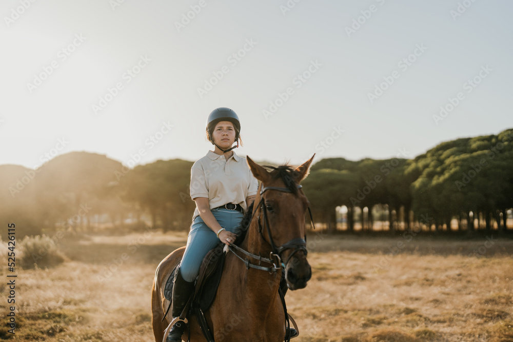 Fototapeta premium backlit photo of a young rider riding a horse