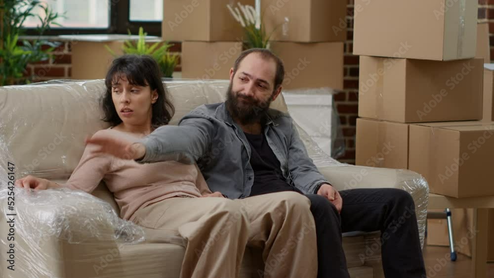 Married couple feeling tired after unpacking furniture and moving in new rented apartment flat, taking break. Sitting on living room couch in household, starting family and lifestyle together. Married couple feeling tired after unpacking furniture and moving in new rented apartment flat, taking break. Sitting on living room couch in household, starting family and lifestyle together.