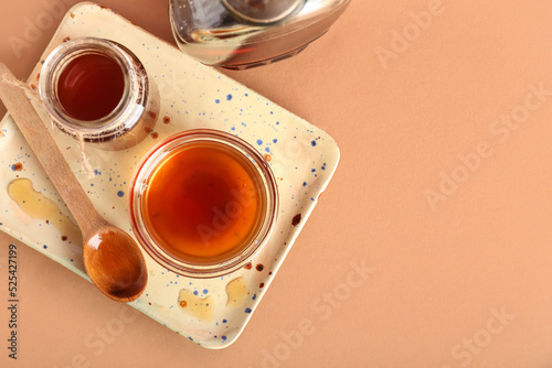 Board with jar and bowl of tasty maple syrup on color background