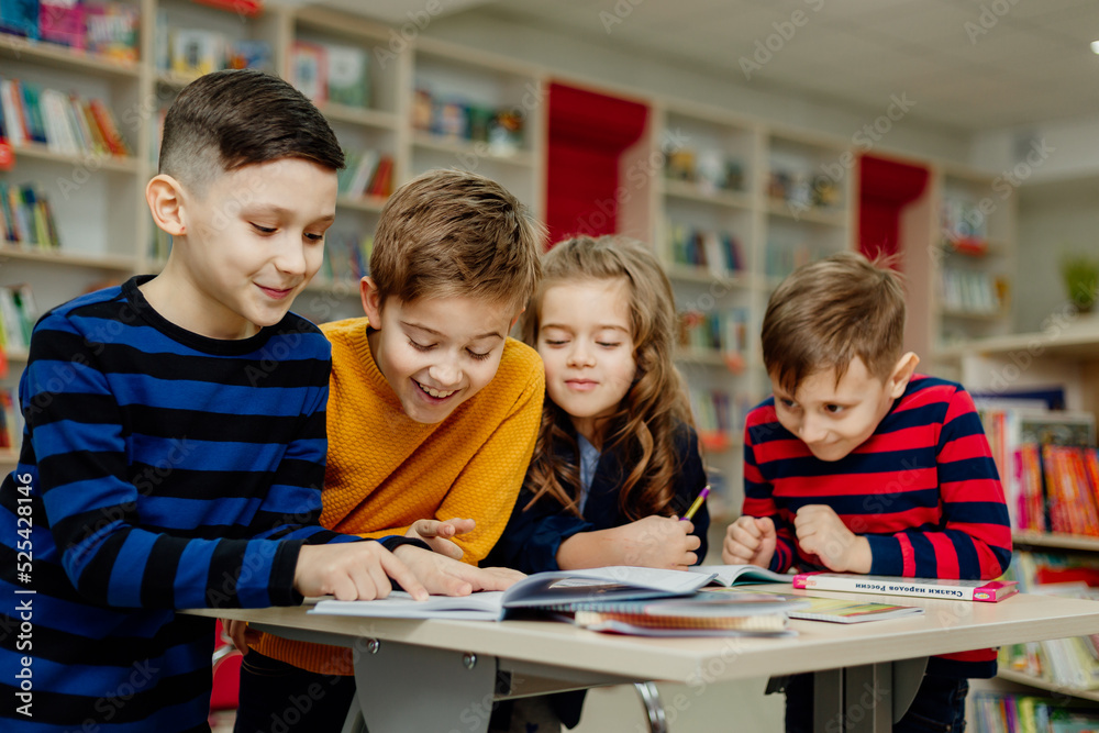 school children in the library reading books, doing homework, prepare a school project for lessons