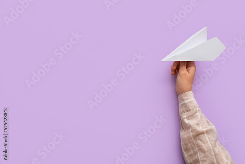 Woman with white paper plane on lilac background