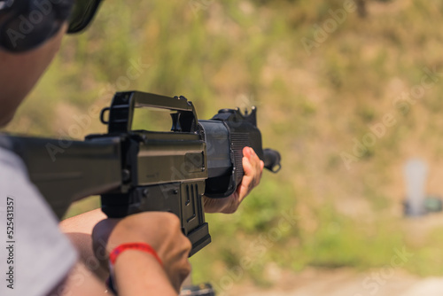 Unrecognizable man aiming shotgun practicing on outdoor firing range. Blurred background horizontal shot . High quality photo