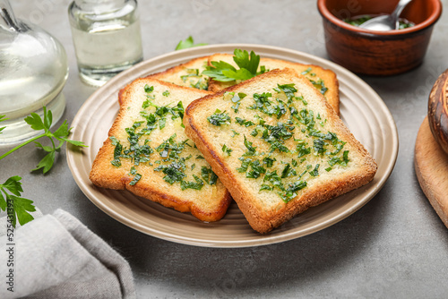 Plate of toasts with garlic and parsley on table