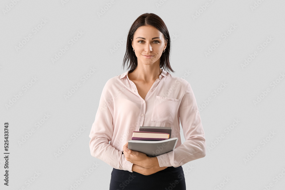 Female Math teacher with calculator and books on light background Female Math teacher with calculator and books on light background