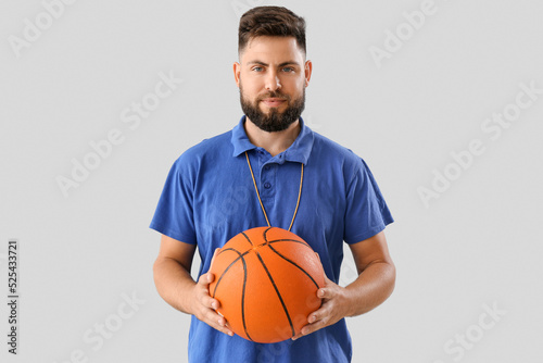 Handsome PE teacher with ball on light background © Pixel-Shot
