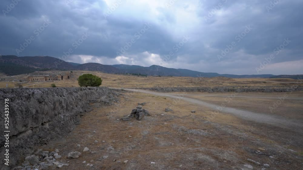 Panning shot of beautiful landscape of Roman ancient ruins of hierapolis Pamukkale with meadow field