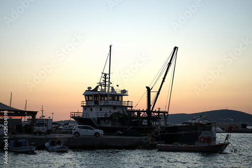 Romantische Abendstimmung mit dem Licht der Abendsonne am Hafen von Ayvalik am Ägäischen Meer mit großem Schiff in der Provinz Balikesir in der Türkei photo