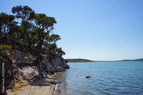 Felsküste mit Strand im Sommer bei blauem Himmel und Sonnenschein in der Bucht vor Ayvalik in der Provinz Balikesir am Ägäischen Meer in der Türkei photo