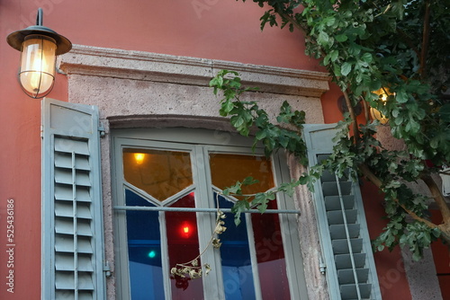 Altes Fenster mit bunten Scheiben, Fensterläden aus Holz und schöner Laterne am Abend in den Gassen der Altstadt von Cunda bei Ayvalik am Ägäischen Meer in der Provinz Balikesir in der Türkei photo