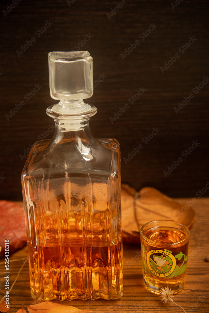 Costa Rican rum served in a shot glass with a frog image, on a wooden table with dry leaves