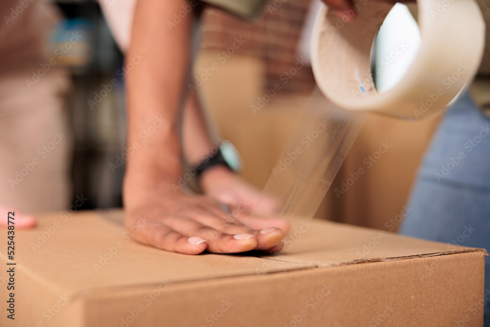 Homeowners packing furniture in boxes with adhesive tape roller, moving in new house bought on mortgage loan. Using sticky scotch to transport cargo storage in real estate property. Close up.