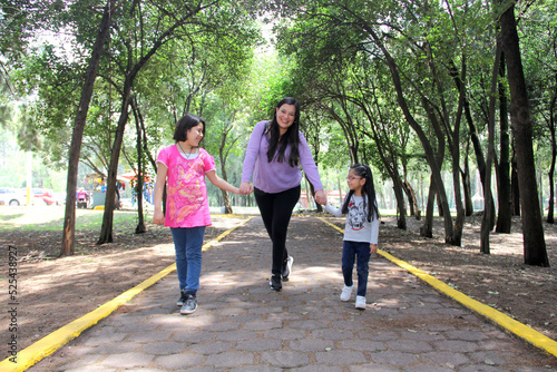 Fototapeta Naklejka Na Ścianę i Meble -  Single and divorced Latin mom and daughters walk in the park outdoors alone spend quality family time on summer vacation or weekend
