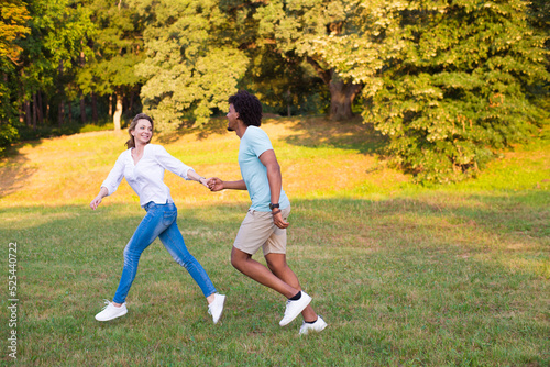 Young happy couple running and playing in the park in spring