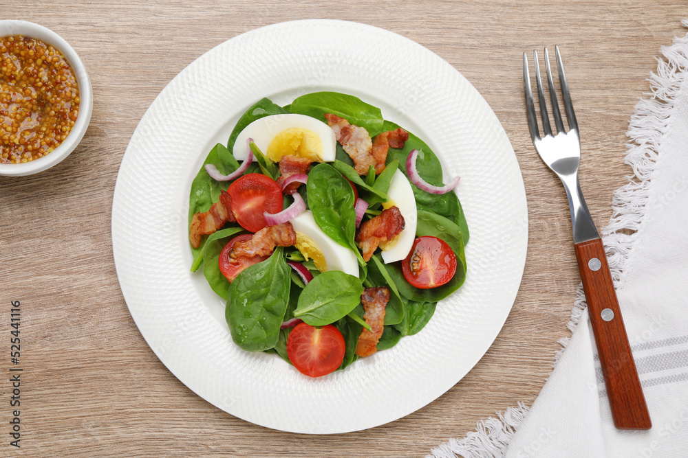 Delicious salad with boiled egg, bacon and vegetables served on wooden table, flat lay