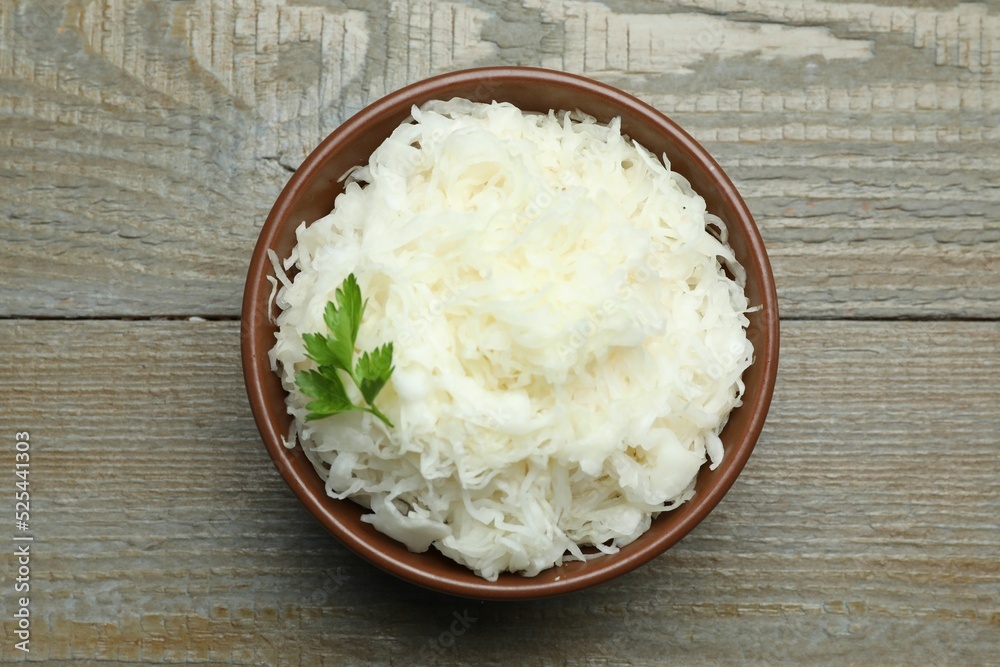 Tasty fermented cabbage with parsley on wooden table, top view Tasty fermented cabbage with parsley on wooden table, top view