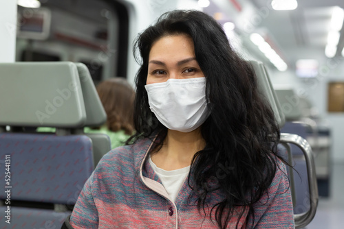 Young adult woman in face mask for disease protection traveling by intercity train