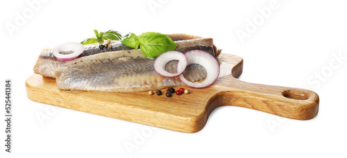 Wooden board with delicious salted herring fillets, onion rings, peppercorns and basil isolated on white