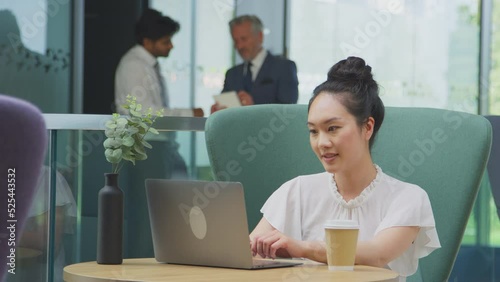 Wallpaper Mural Businesswoman using laptop working at table and drinking takeaway coffee in breakout seating area of office building - shot in slow motion  Torontodigital.ca