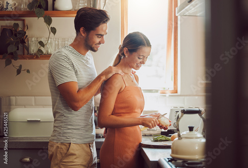 Romantic, caring and loving young couple supporting each other while preparing a meal in the kitchen. Man and woman in a happy, stressless and relaxed relationship together cooking at home. photo