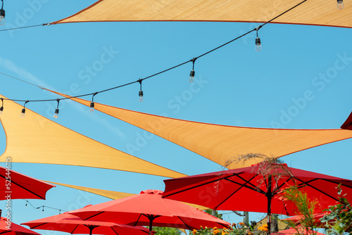 Photographie Multiple triangle shaped yellow nylon sunshades and awnings hanging over a patio deck