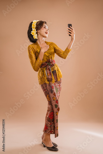 happy young balinese woman take her selfie portrait using smartphone