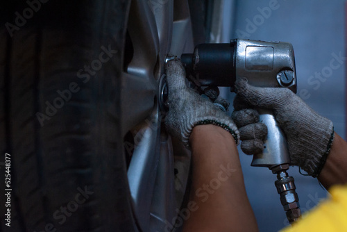 Hands of mechanic changing car wheel in auto repair service with Impact Wrench