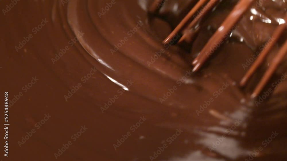 Mixing melted liquid dark chocolate with a whisk. Close up of liquid hot chocolate swirl for making ice cream Mixing melted liquid dark chocolate with a whisk. Close up of liquid hot chocolate swirl for making ice cream