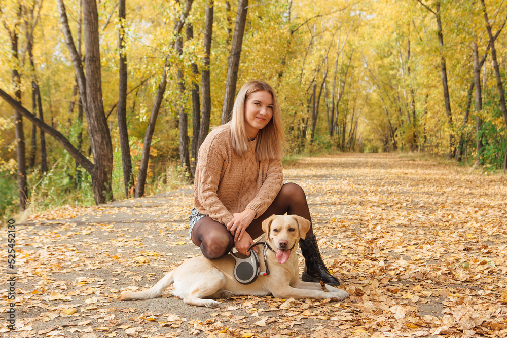A young woman walking with her beloved labrador dog in autumn park. A young woman walking with her beloved labrador dog in autumn park.