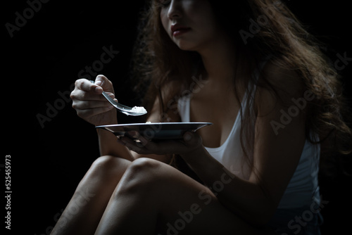 Homeless. Homeless woman eating food in the dark light of the building corner