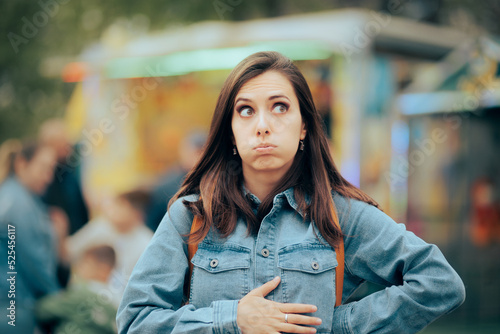 Woman Feeling Hungry Looking for Something to Eat in Amusement Park. Person accusing stomachaches after eating street food at funfair festival
 photo