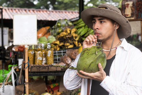Latin young man drinking coconut water in the market photo