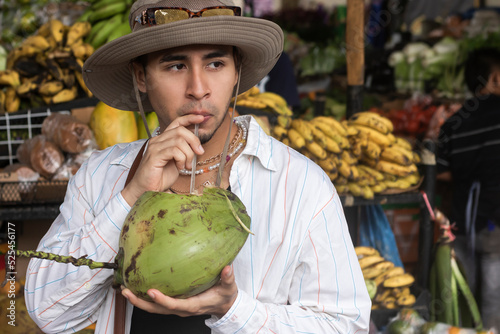 Latin young man drinking coconut water in the market photo
