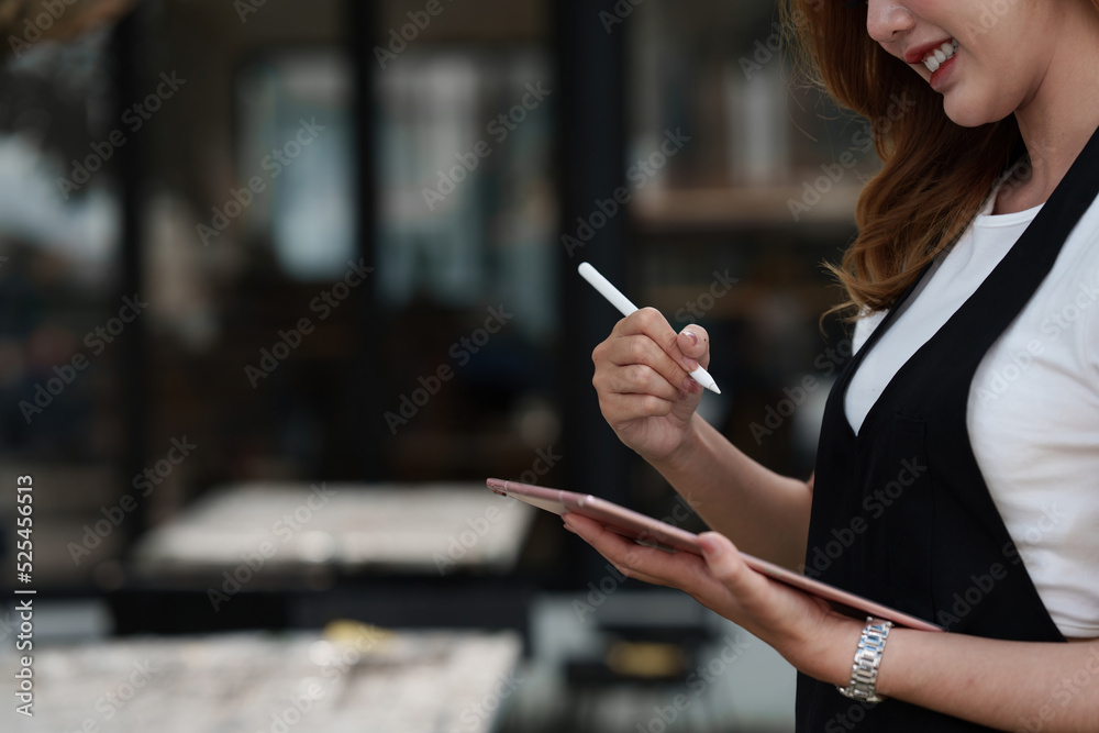Beautiful Asian women Barista smiling and using tablet at her cafe Beautiful Asian women Barista smiling and using tablet at her cafe