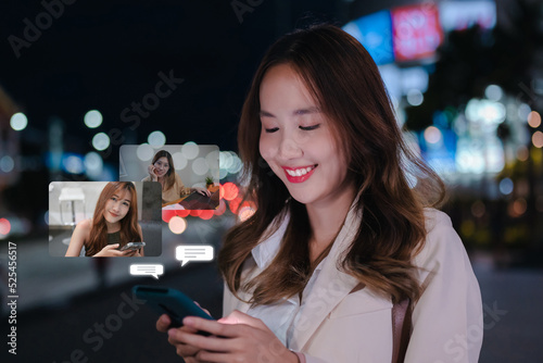 Asian businesswoman using mobile phone and talking with friend popup futuristic technology her enjoy smiling in the city after work at night traffic light. People lifestyle concept.