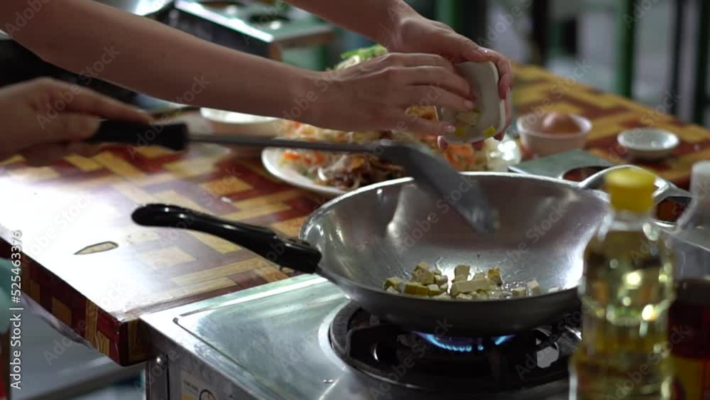 2 People Cooking Tofu in a Wok over Medium Heat to Cook Pad Thai in an Outdoor Kitchen in Bangkok Thailand SLOW MOTION 2 People Cooking Tofu in a Wok over Medium Heat to Cook Pad Thai in an Outdoor Kitchen in Bangkok Thailand SLOW MOTION
